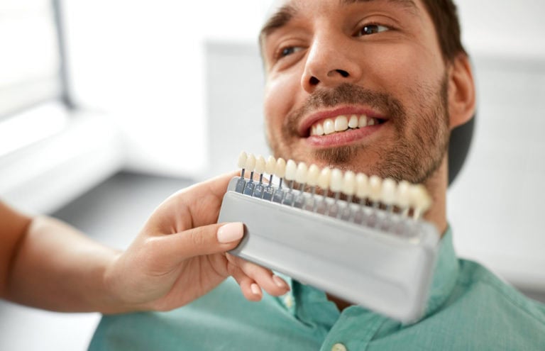 Zahnarzt wählt Zahnfarbe für Patienten in der Klinik