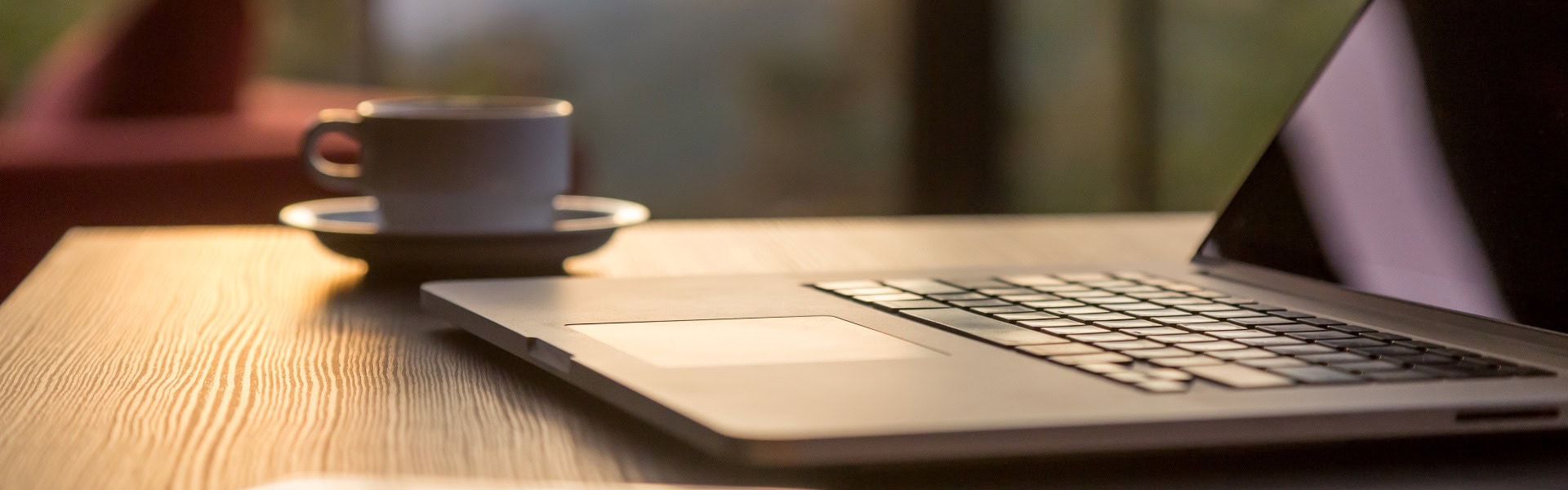 Computer Kaffeetasse und Telefon auf schwarzem Holztisch Sonne aufgeht